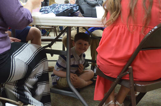 Child under table smiling at the camera